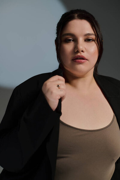 Красивая женщина plus size уверенно демонстрирует свой стиль, позируя в трикотажном наряде.