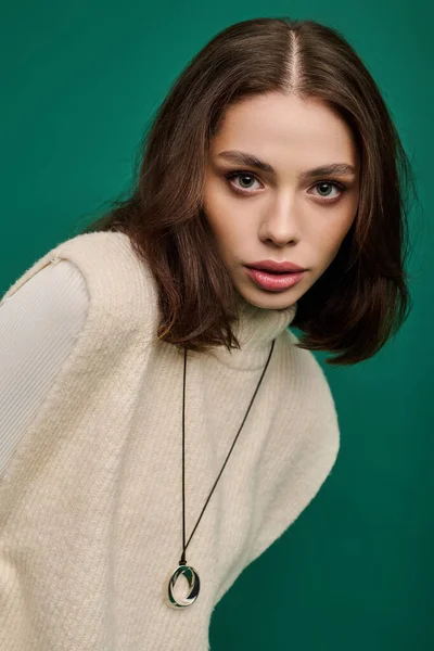 Güzel genç bir kadın şık bir kıyafet ve çarpıcı bir kolyeyle moda anlayışını sergiliyor..