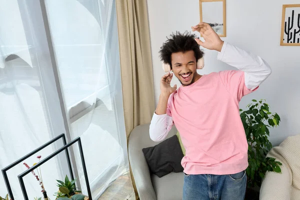 Neşeli genç adam müzik eşliğinde dans ediyor, bitkilerle dolu şık bir oturma odasında kulaklık takıyor..