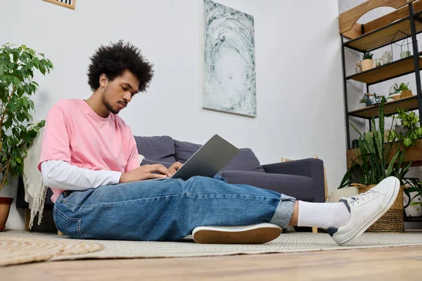 Genç ve yakışıklı bir adam parlak ve davetkar bir oturma odasında dizüstü bilgisayarına odaklanıyor..