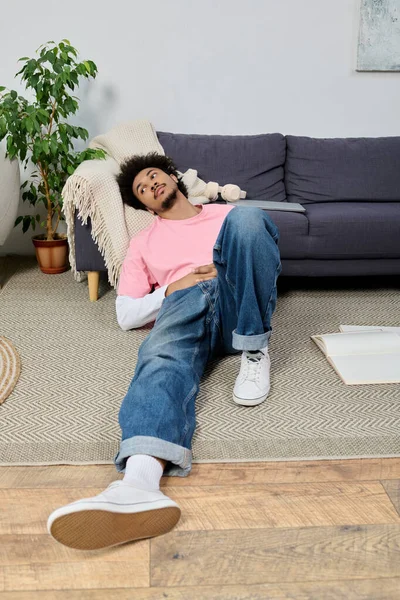 Genç ve yakışıklı bir adam yerde rahatça uzanır, rahat ve rahat hisseder..