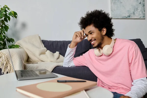 Genç, yakışıklı bir adam şık oturma odasından çevrimiçi bir konuşma yaparken gülümsüyor..