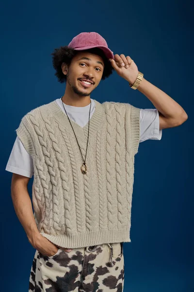 Neşeli genç adam sevimli kişiliğini ve modasını sergileyen rahat bir kazak ve şapka giyiyor..