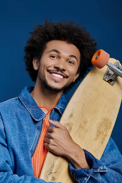 Genç adam kaykayı tutarken, genç enerjisini ve tarzını somutlaştıran parlak gülümseme mutluluk saçıyor..