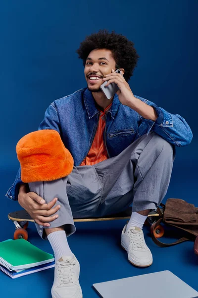 Genç, şık bir adam canlı bir telefon görüşmesi yapar, kaykayının yanında öylesine oturur..