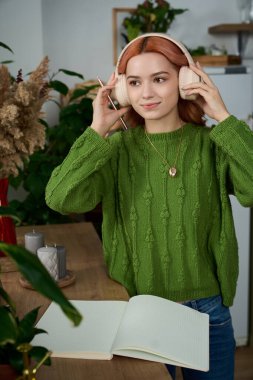 Sıcak saçlı çekici kadın, yemyeşil ve yaratıcılığın ortasındaki müzikten hoşlanıyor..