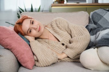 Kanepede dinlenen genç ve güzel bir kadın konforla çevrili sakin bir öğleden sonranın tadını çıkarıyor..