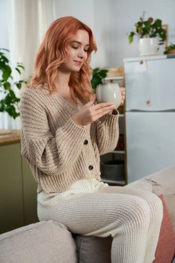 Güzel genç bir kadın rahatça oturur, içkisinin tadını çıkartır, rahat, güzel dekore edilmiş bir yerde.