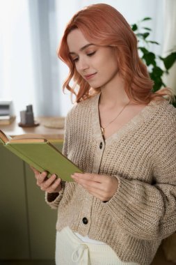 A beautiful young woman reads intently, surrounded by a warm and inviting atmosphere.