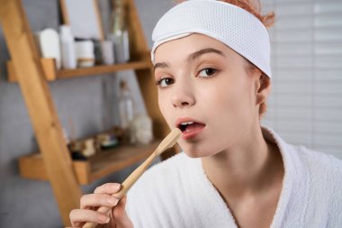 Sabah ışığı odayı dolduruyor. Genç ve güzel bir kadın dişlerini fırçalarken, rahat..