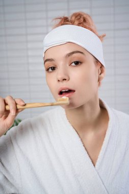 Dişlerini sıcacık bir banyoda fırçalarken kendine bakmanın keyfini çıkaran genç bir kadın.