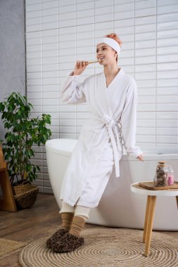 Beyaz cüppeli bir kadın huzur dolu bir banyoda uzanırken zevkle atıştırıyor..