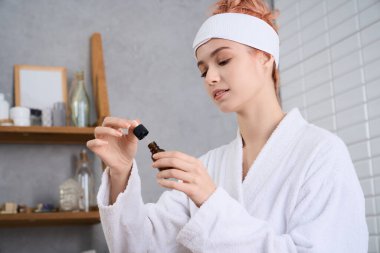 Rahat bir bornoz içindeki sakin bir kadın, sakin bir yerde, sakin bir şekilde gerekli yağı ölçer..