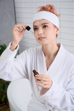 Güzel genç bir kadın, banyoda dinlenirken rahatlatıcı bir cilt bakım rutininden hoşlanır..