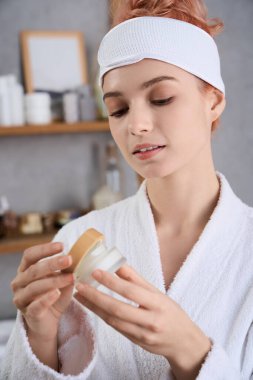 Güzel genç bir kadın en sevdiği kremi rahatlatıcı bir banyo atmosferinde inceliyor..