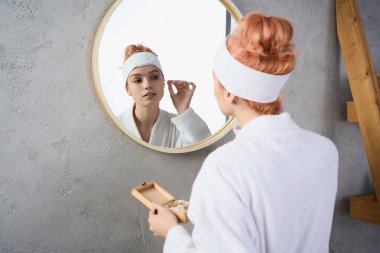 Genç bir kadın şık bir banyoda cildini besler, kendine olan sevgisini şekillendirir..