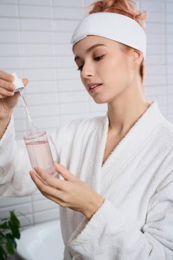 Güzel genç bir kadın evde huzurlu bir cilt bakımının keyfini çıkarırken serumu dikkatlice uyguluyor.