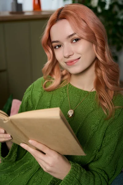 Genç bir kadın en sevdiği kitabı okurken gülümsüyor..