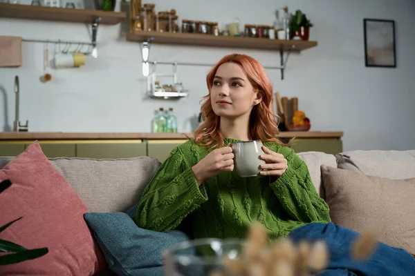 Dalgalı saçlarını kupadan yudumlayan, rahat evinin sıcaklığını kucaklayan hayat dolu genç bir kadın..