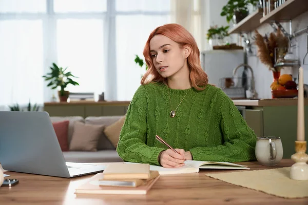 Yeşil kazaklı güzel bir kadın karşılama odasında otururken derslerine odaklanıyor..