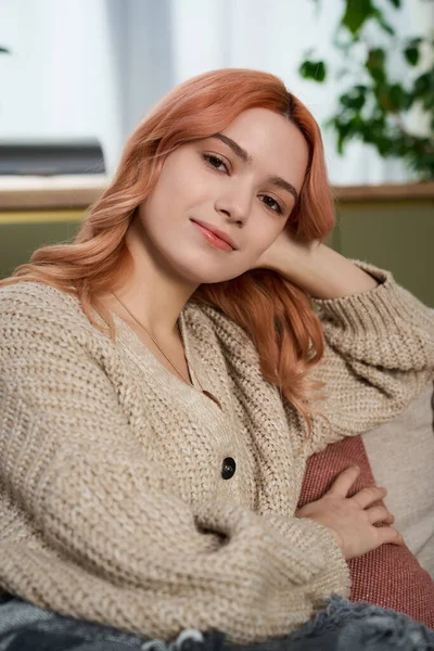 Işıl ışıl aydınlatılmış odada pembe saçlı, somut rahatlığı ve zarafeti olan hoş bir genç kadın var..