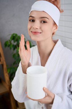 Bornozlu ve neşeli bir kadın, rahatlatıcı bir spa ortamında cilt bakımını paylaşır..