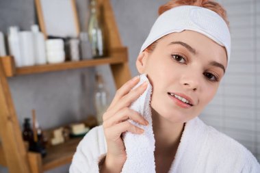 Güzel, genç bir kadın tenini önemserken sakin, minimalist bir yerde parıldıyor..