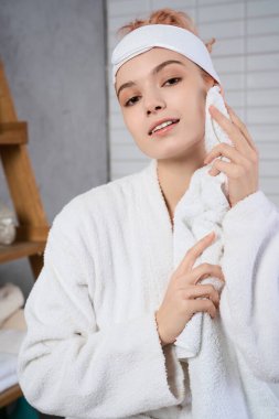 Genç bir kadın cilt bakımı rutininden zevk alır, sakin bir spa ortamında yüzünü nazikçe siler..