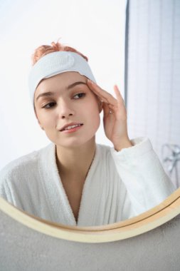 Parlak ve sakin bir ortam, cildini nazikçe önemseyen genç ve güzel bir kadının etrafını sarıyor..