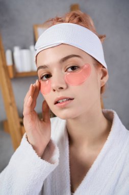 Genç bir kadın spa 'da rahatlatıcı bir andan zevk alıyor. Rahatlarken göz tedavisini uyguluyor..