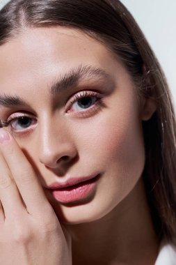 Işıl ışıl cildi ve anlamlı gözleri olan genç bir kadın nazikçe yüzüne dokunuyor, zarafeti çağrıştırıyor..