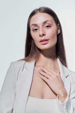 Şık giyinmiş çarpıcı genç bir kadın zarif bir şekilde duruyor, kendine güveni ve cazibesi tam..