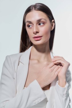 Sevimli genç bir kadın minimalist bir ortamda zarif bir poz veriyor. Güzellik ve tarz sergiliyor..