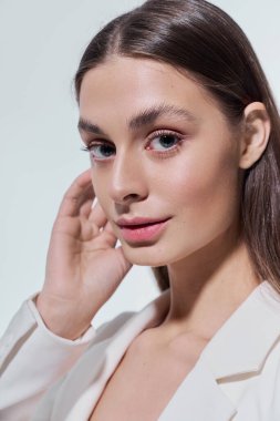 Kendine güvenen genç bir kadın zarif güzelliğini sergileyerek şık bir kıyafet içinde parlıyor..