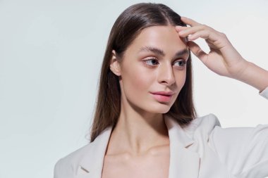 Güzel, genç bir kadın zarif pozlar veriyor, zarif yüz hatlarını ve şık tarzını vurguluyor..