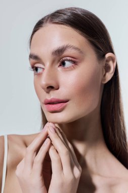 Güzel, genç bir kadın düşünceli bir şekilde ışıl ışıl cildini ve narin cazibesini sergiliyor..