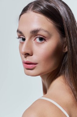 Güzel genç bir kadın zarif pozlar veriyor, pürüzsüz cildini ve büyüleyici yüz ifadesini sergiliyor..