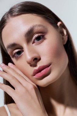 Güzel genç bir kadın zarif bir şekilde poz veriyor, sakin ifadesini ve kusursuz cildini vurguluyor..