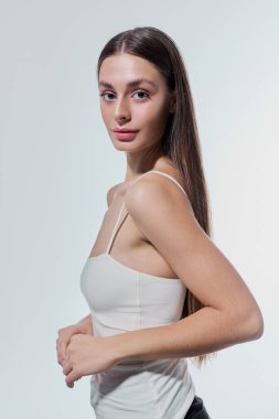 A stunning young woman poses gracefully, showcasing her natural beauty against a soft backdrop.