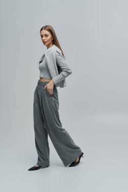 Zarif genç kadın şık kıyafetini minimalist bir ortamda sergiliyor..