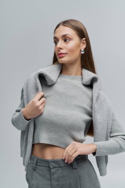 Kendine güvenen genç bir kadın modern modayı şık gri bir elbiseyle sergiliyor..