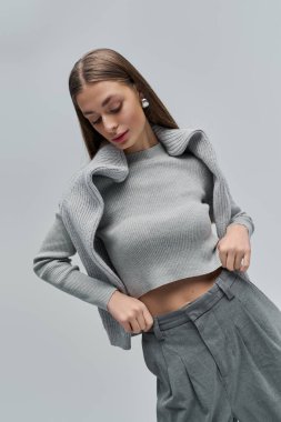 Genç ve güzel bir kadın, modaya uygun gri bir elbise ve minimalist bir arkaplan modeli..