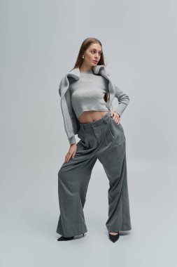 Şık gri elbiseli kendine güvenen genç bir kadın zarafet ve tarz saçar..