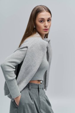 Güzel genç bayan zarif bir şekilde duruyor, şık bir kıyafet giyiyor ve kendine güveni tam..