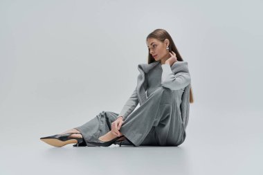 Zarif genç bir kadın zarif bir şekilde rahat bir elbiseyle oturur, sakin bir yerde ışıldayan bir güzellik..