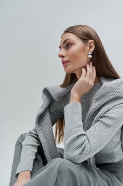 Göz kamaştırıcı genç bir kadın, sakin bir ortamda şık bir kıyafetle şık bir poz verir..