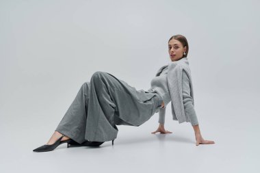 Güzel genç bir kadın zarif bir şekilde yaslanarak moda anlayışını sergiliyor..