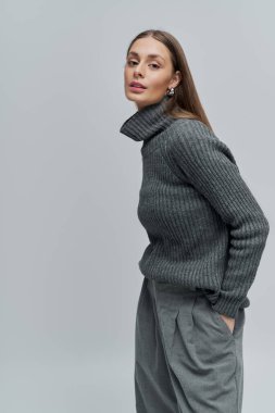 Zarif genç kadın şık bir süveter ve özel dikim pantolonla tarzını sergiliyor..