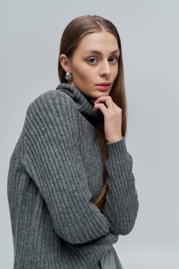 Büyüleyici genç bir kadın, çenesini eline dayayıp, tarzını sergiliyor..