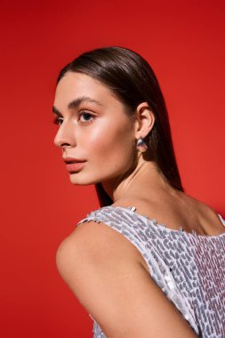 Güzel, genç bir kadın, uzun saçlı, kendine güveni ve tarzıyla omzunun üzerinden bakıyor..